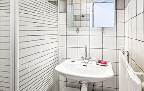 Un bagno con lavandino bianco, uno specchio e un termosifone.