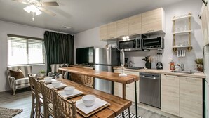 A modern kitchen with wooden cabinets, stainless steel appliances, and a dining area with a wooden table and chairs. - Designer Condo in Hip Zen Yard! Midtown Phoenix! (Phoenix)