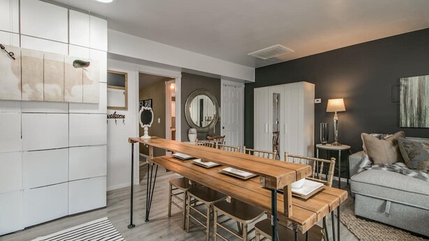 A modern kitchen with a wooden dining table, white cabinets, and a grey sofa in the living area. - Designer Condo in Hip Zen Yard! Midtown Phoenix! (Phoenix)