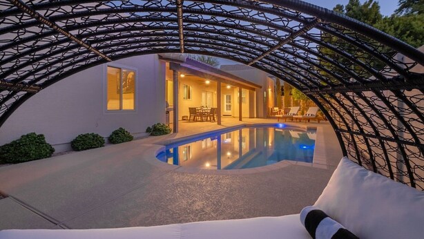 Ein Poolbereich mit überdachter Sitzgelegenheit, einem Schwimmbecken und einem Haus im Hintergrund.