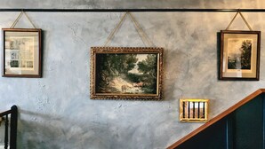 A staircase with a handrail, a wall with three framed pictures, and a small window with blinds. - South Court Inn (Luray)