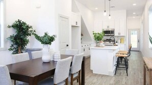 A modern kitchen with white cabinetry, a central island, and pendant lighting.