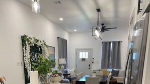 A modern kitchen with white cabinetry, a central island, and a dining area with a table and chairs.