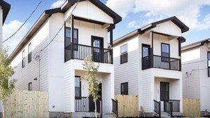 A modern apartment building with a flat roof, white exterior, and black railings on balconies.