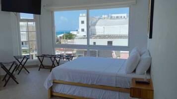 A bedroom with a bed, a TV, and a view of the city.