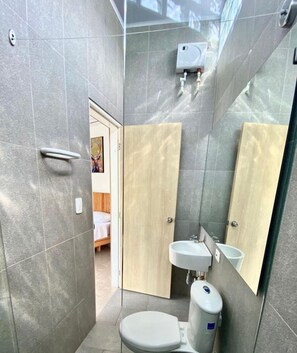 Eenvoudige tweepersoonskamer | Badkamer | Een douche, een regendouche, handdoeken, zeep