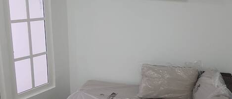 A room with a bed, a television mounted on the wall, and a window.
