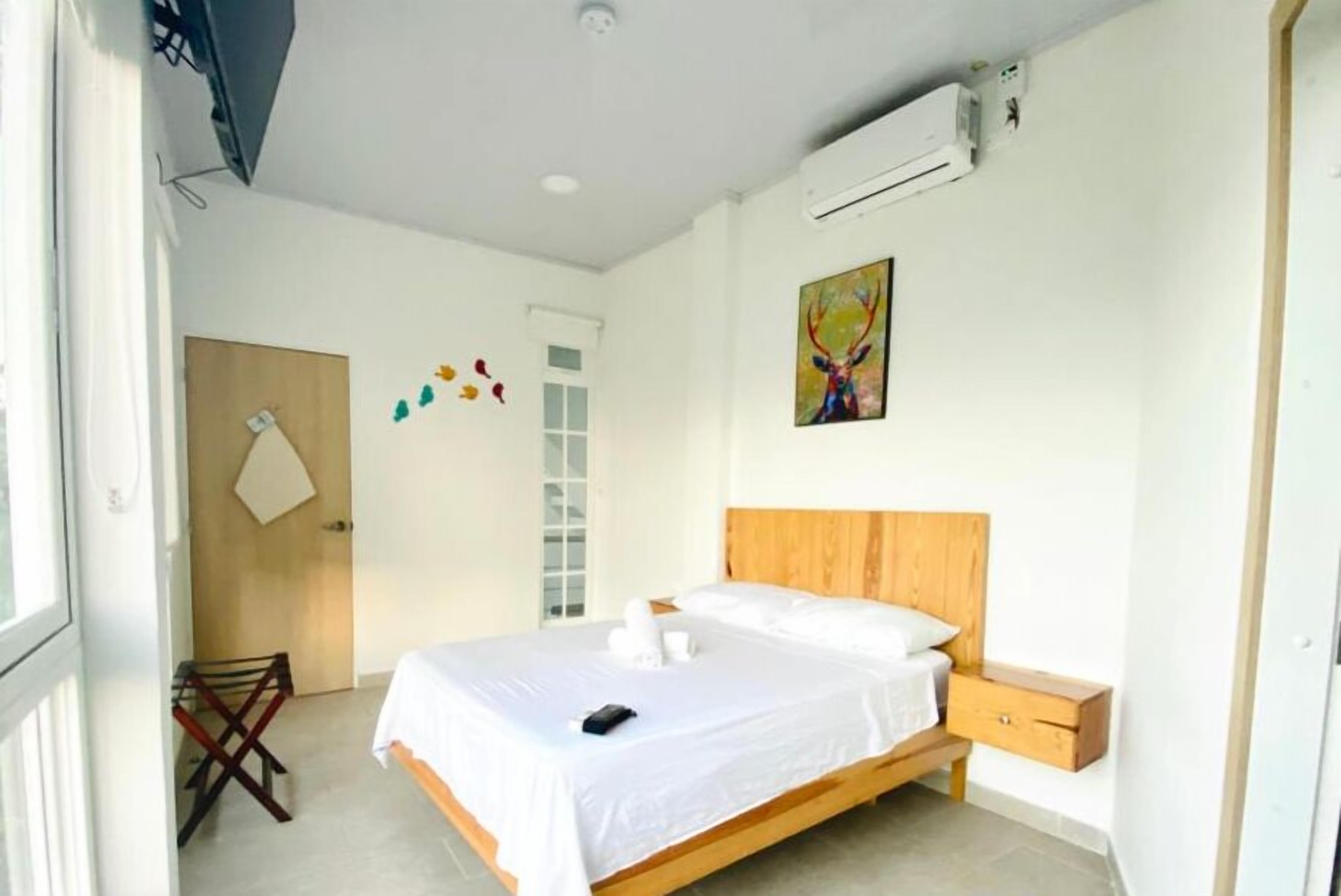 Un dormitorio con una cama de madera, una mesita de noche, una silla y una puerta que da a otra habitación.
