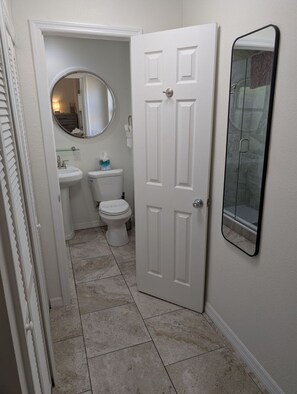 A bathroom with a toilet, sink, and mirror. - #3-TwinPalms-King Studio Suite-3-min Walk to Siesta Key Beach, Heated Pool (Siesta Key)