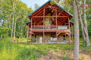 A cabin with a stone foundation, wooden exterior, and a balcony.