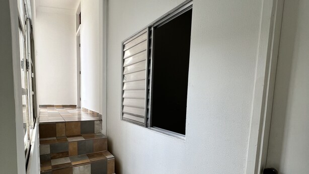 A staircase with a checkered tile pattern leading to a door with a window. - Grande Familia Hostel (São Paulo)