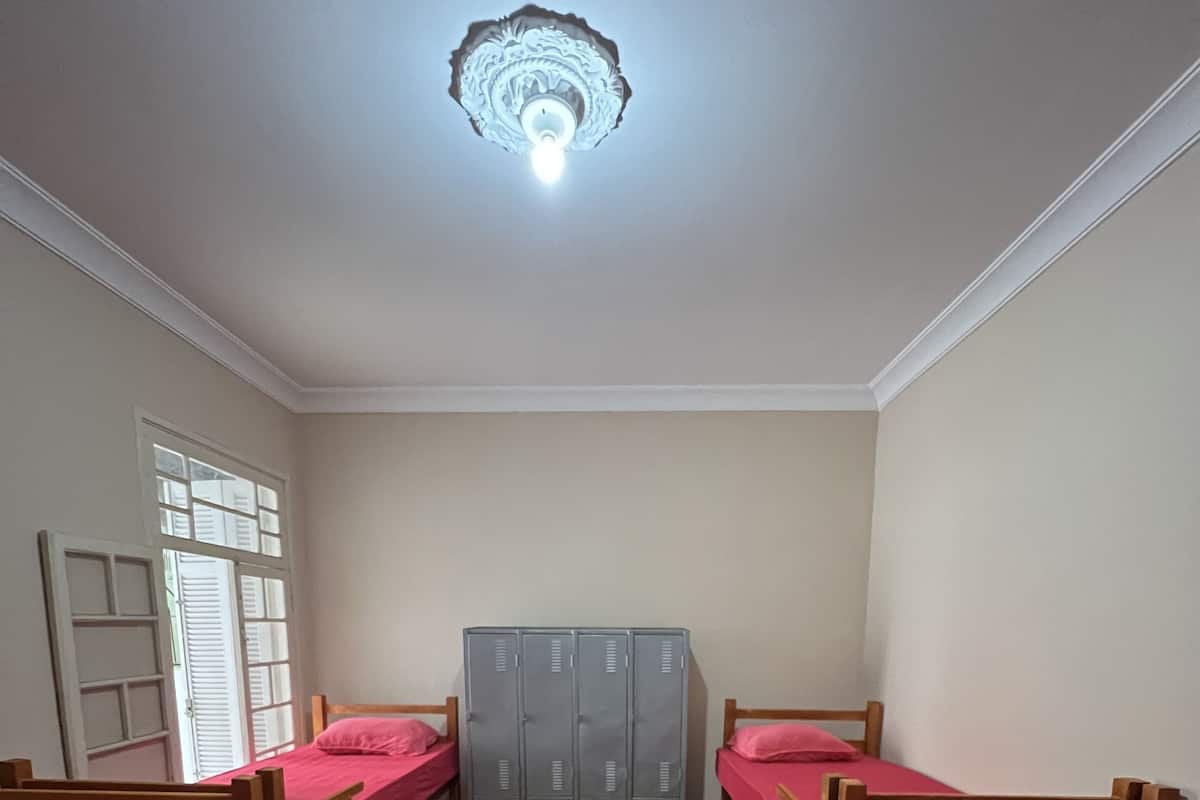 Une chambre de dortoir avec des lits superposés, une armoire et un luminaire au plafond.