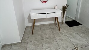 A white vanity with a mirror, a small white cabinet, and a potted plant. - Grande Familia Hostel (São Paulo)