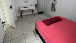 A bedroom with a bed, a desk, a mirror, and a door. - Grande Familia Hostel (São Paulo)