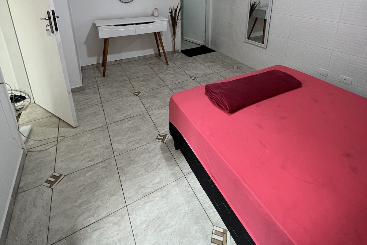 Une chambre à coucher avec un lit, un bureau, un miroir et une porte.