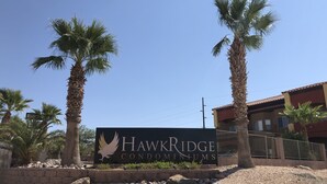 Une enseigne indiquant le complexe de condominiums Hawk Ridge, avec des palmiers et un ciel dégagé.