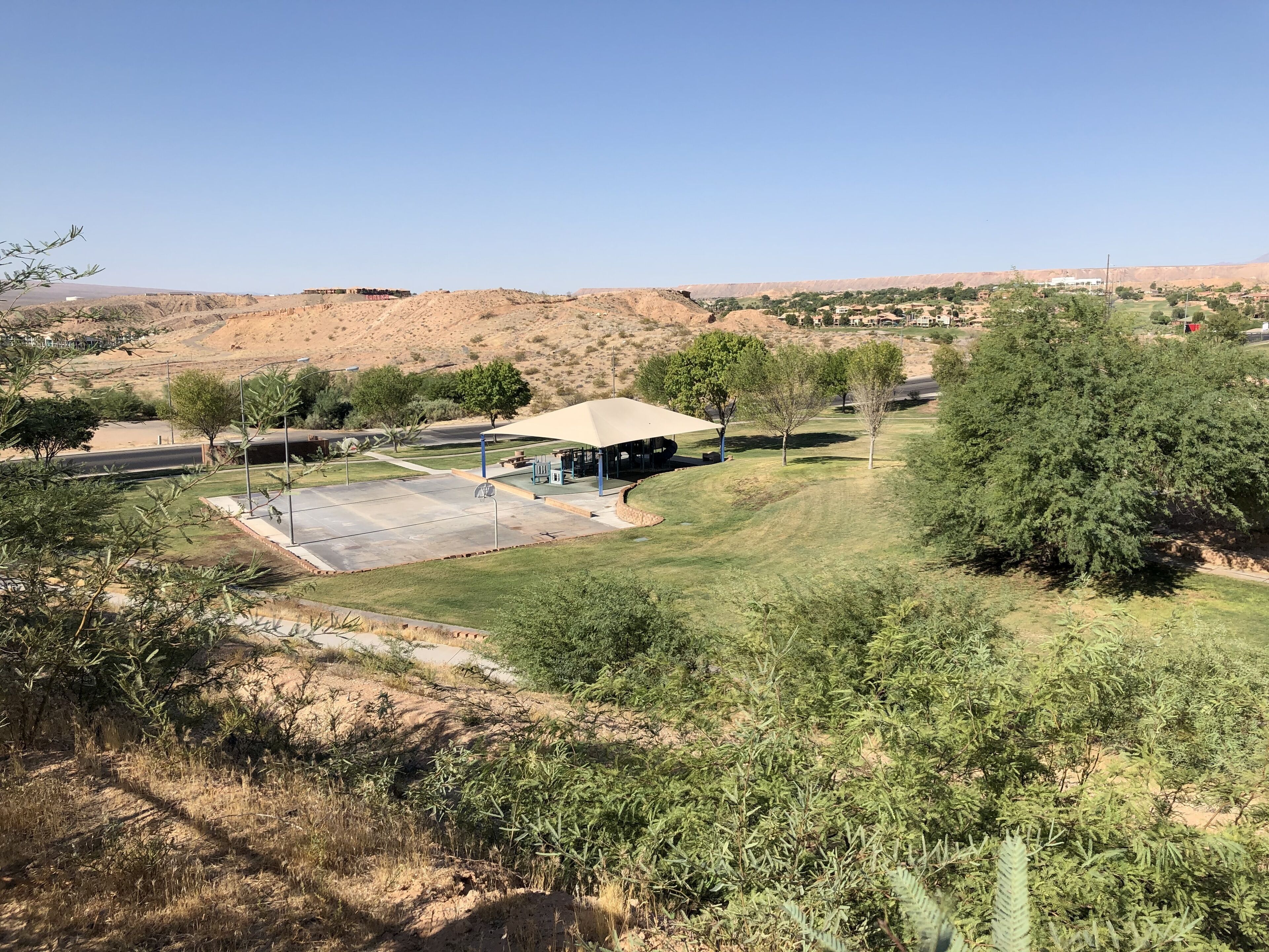 Um parque com área de estar coberta, parquinho infantil e mesa para piquenique.