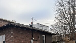 En murstensvilla med en lille tilhørende garage, en støbt indkørsel og en græsplæne dækket af blade.