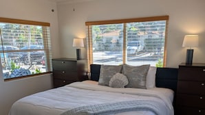 A bedroom with a bed, two bedside tables, a ceiling fan, and large windows with blinds. - #8-TwinPalms-King Studio Suite (Siesta Key)