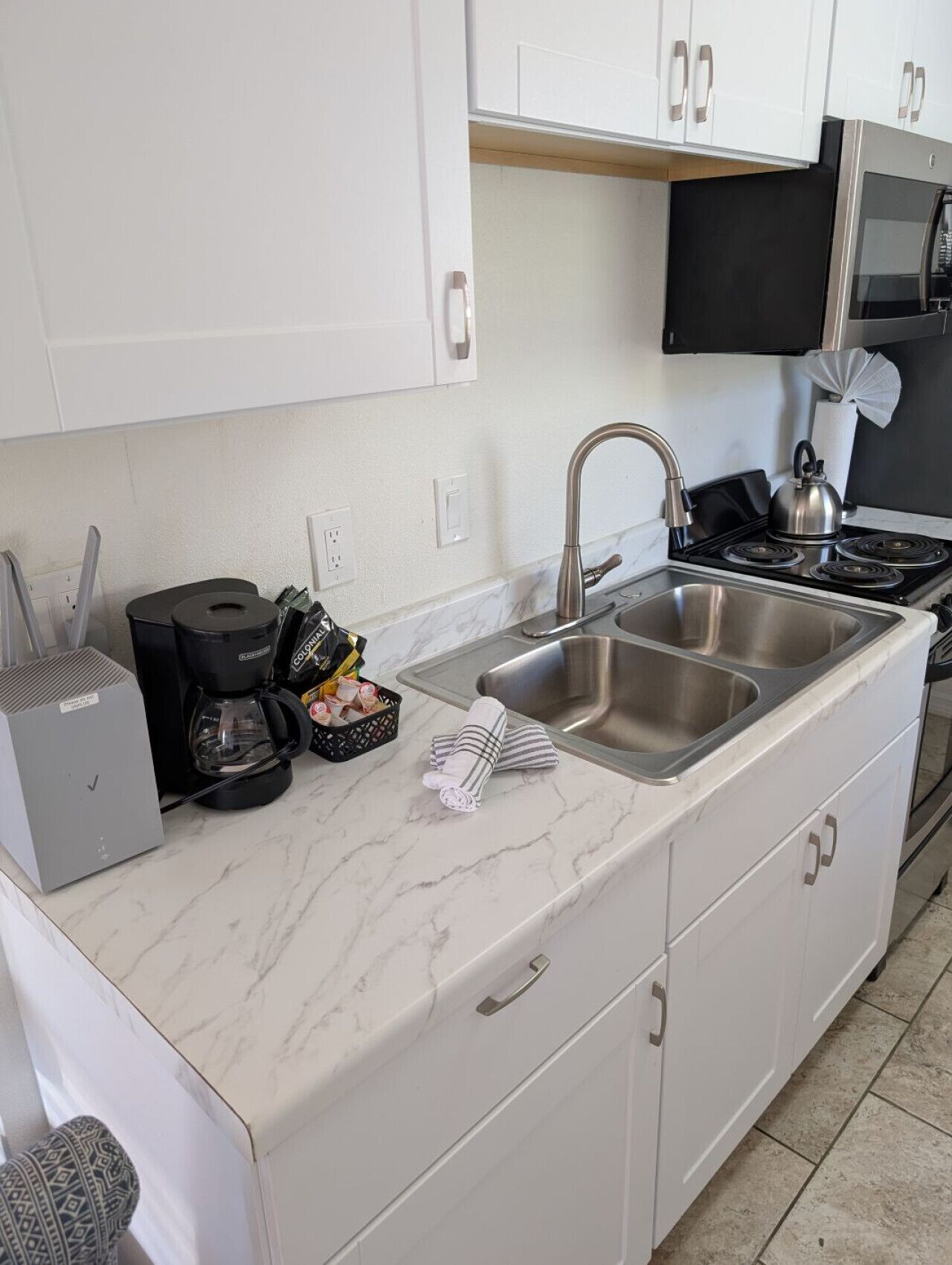 A compact kitchen with a sink, stove, and coffee maker.