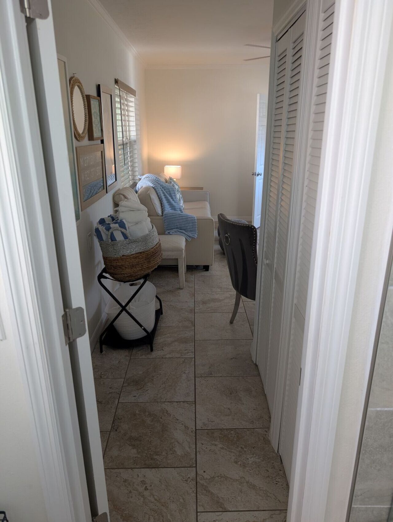 A narrow hallway with a tiled floor, a white door on the left, and a closed door on the right.