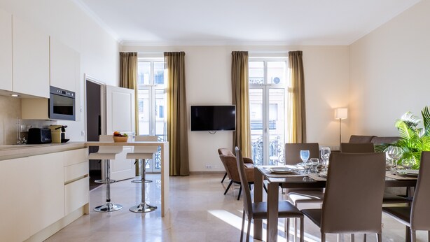 A modern hotel room with a kitchen, dining area, and a balcony with a view. - 2-Br. steps from the Palais des Festivals (Cannes)