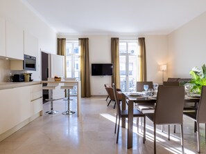 Une chambre d’hôtel moderne dotée d’une cuisine, d’un coin repas et d’un balcon avec vue.