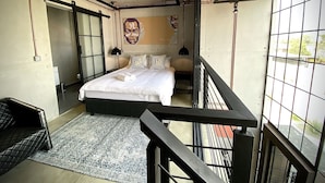 A bedroom with a bed, a window, a door, and a small balcony. - The Cubes Apartments (Lusaka)