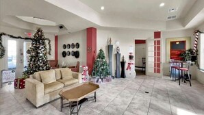 Eine geräumige Lobby mit einem großen beigen Sofa, einem Couchtisch, einem Weihnachtsbaum und einer Wand mit verschiedenen Dekorationselementen.
