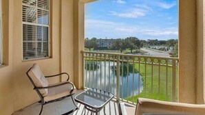 Ein Balkon mit Blick auf einen See, ein Stuhl und ein Tisch.