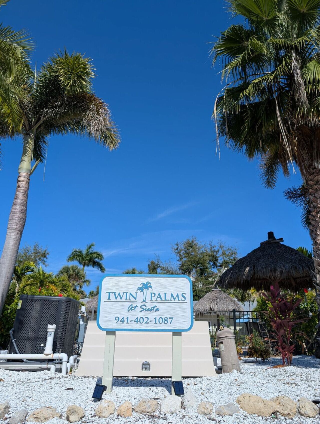 Un panneau indiquant l’emplacement du complexe hôtelier Twin Palms, avec un numéro de téléphone à contacter.