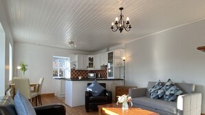 A living room with a sofa, a coffee table, and a dining area with a table and chairs. - Cottage 433 - Ballyconneely - sleeps 2 guests  in 1 bedroom (Ballyconneely)