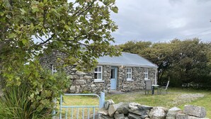 A stone house with a blue door, a stone wall, and a metal gate. - Cottage 433 - Ballyconneely - sleeps 2 guests  in 1 bedroom (Ballyconneely)