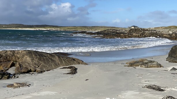 A rocky beach with waves crashing onto the shore, a sandy beach in the foreground, and a building on the right side. - Cottage 433 - Ballyconneely - sleeps 2 guests  in 1 bedroom (Ballyconneely)