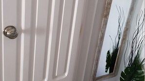 Een witte deur met verticale panelen en een zilveren handgreep.