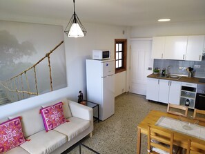 A compact living space with a kitchenette, a sofa with patterned cushions, and a dining table.