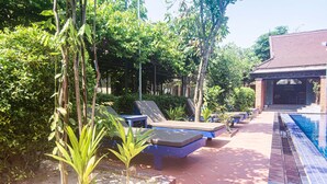 Un área de piscina con sillones reclinables y un suelo de baldosas.
