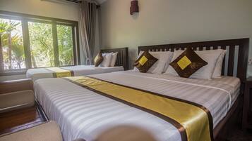 Quarto de hotel com duas camas, uma janela grande e vista para o verde lá fora.