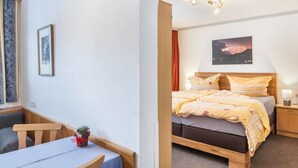 Een slaapkamer met een bed, nachtkastje, lamp en een lijst met een afbeelding aan de muur.