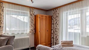 Ett hotellrum med en säng, en garderob, ett element och gardiner.
