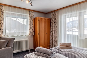 A hotel room with a bed, a wardrobe, a radiator, and curtains.