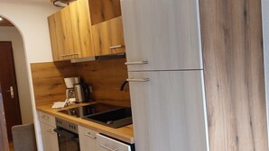 Ett kök med träskåp, en diskho i rostfritt stål och en kaffebryggare.