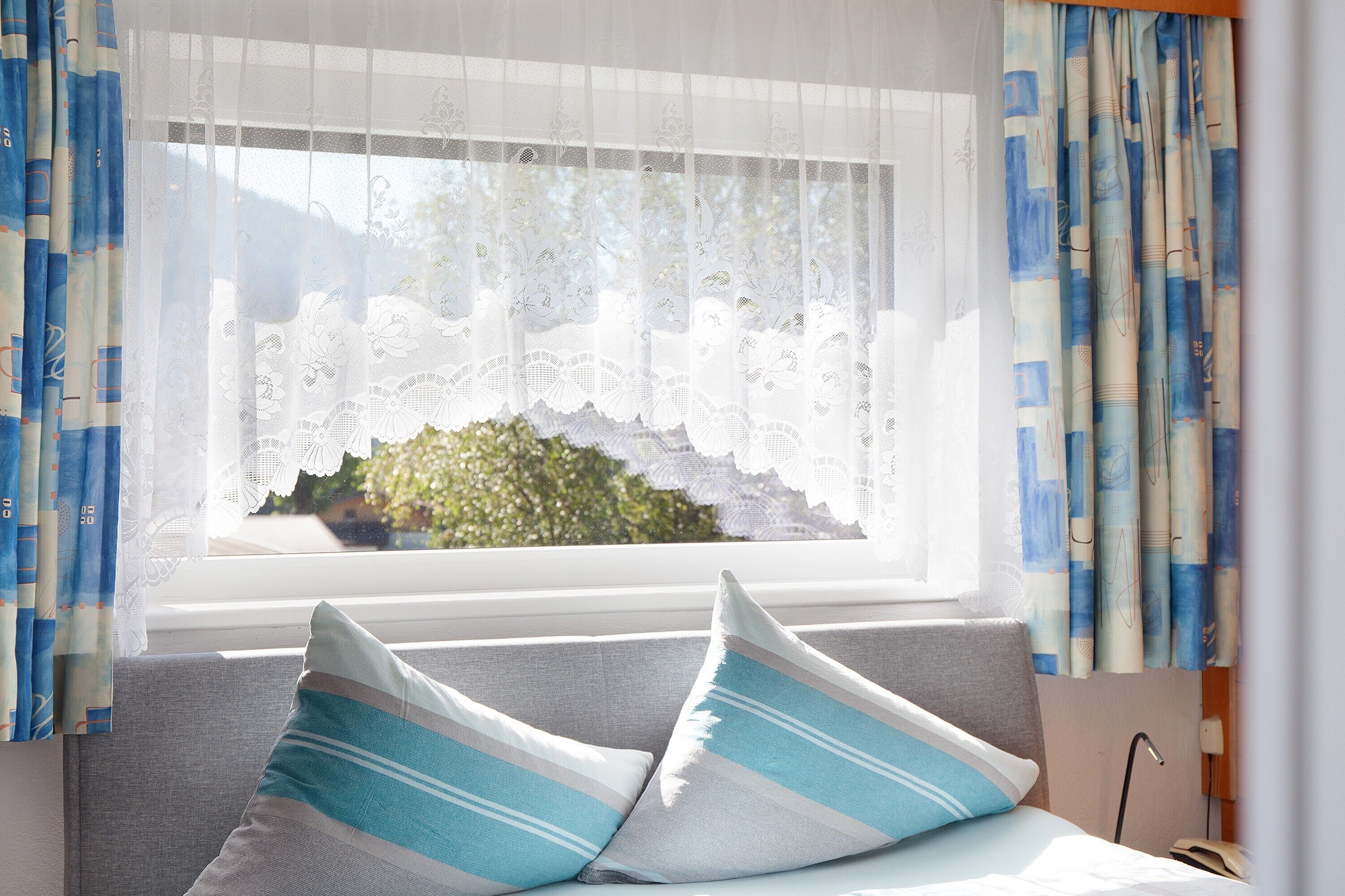 Una habitación con ventana, un sofá y dos almohadas.