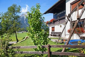 Blick auf Berge, ein Holzzaun und ein Gebäude mit der Aufschrift 'Haus Lärchenhaus'.