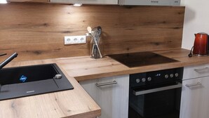 Una cocina moderna con encimera de madera, horno empotrado y estufa.