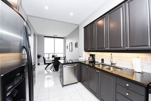 Enjoy cooking in this well-equipped kitchen with a large island, sink, and stainless steel refrigerator.