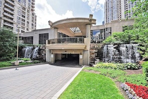 Stunning building with a curved entrance and lush green surroundings, featuring a glass balcony and waterfalls in the background.