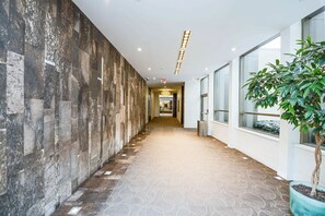 Stylish corridor with patterned carpet and a textured wall, leading to a reception area.