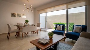 Un salon moderne comprenant un coin repas, un ensemble de canapés et une grande porte-fenêtre coulissante donnant sur un balcon.