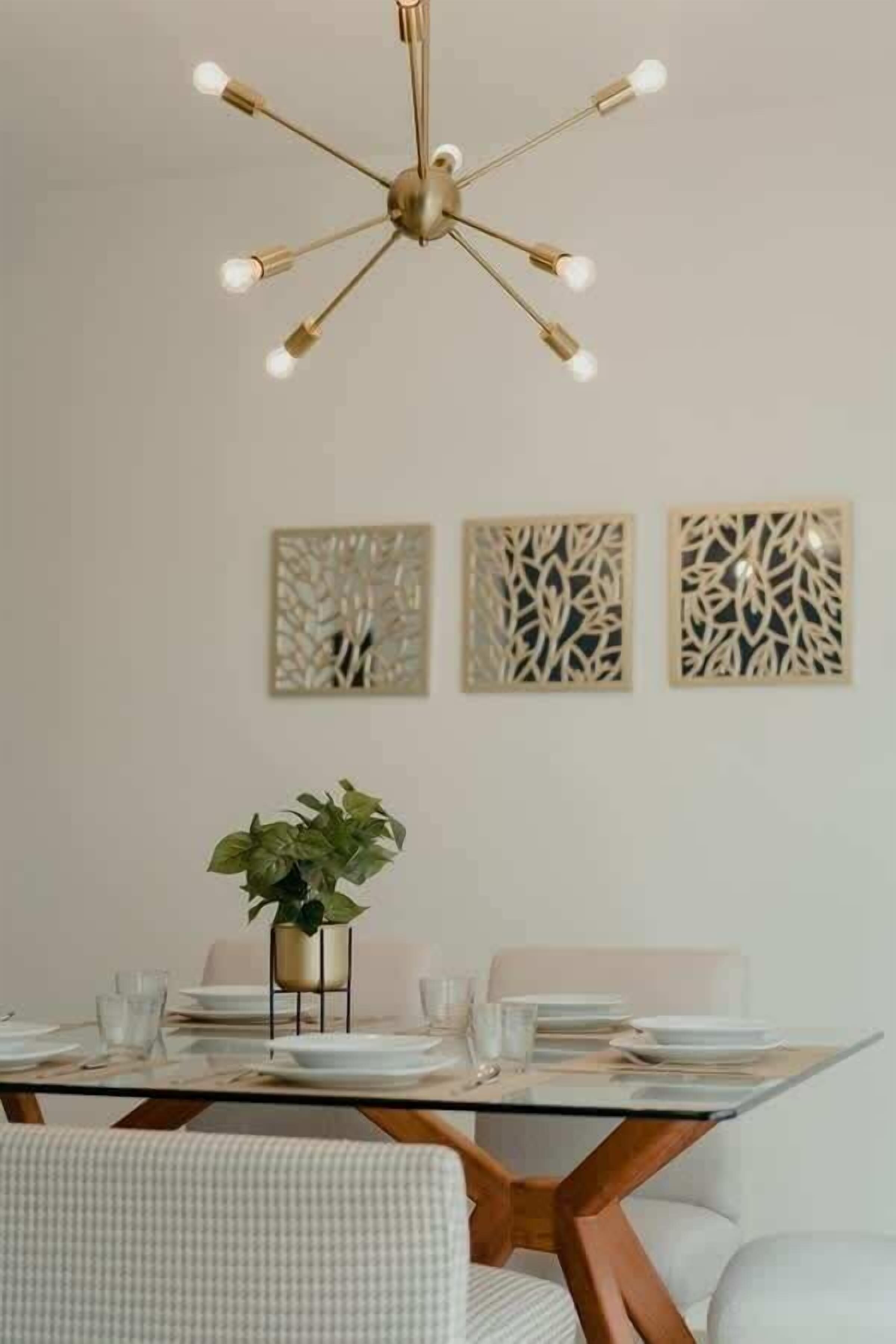 A dining area with a glass table, white chairs, and a central plant.